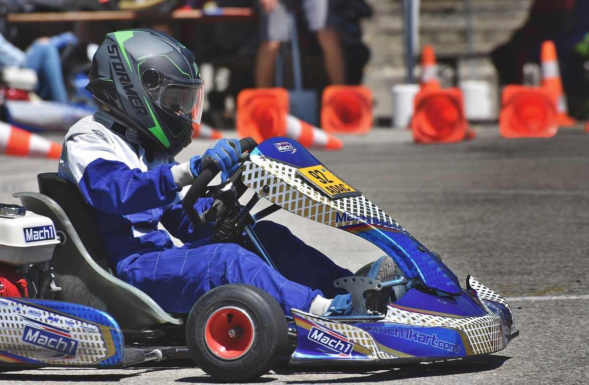 Un coureur en combinaison bleue conduit un kart bleu sur circuit