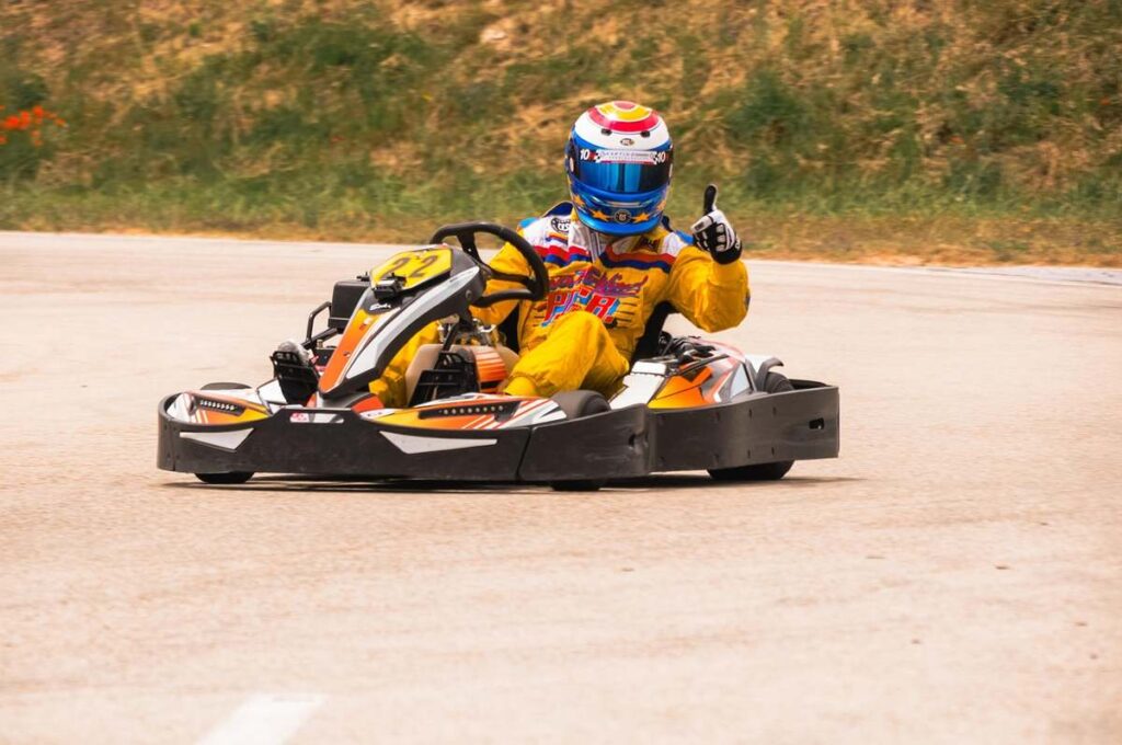 Un pilote de karting donne un signe de victoire sur la piste