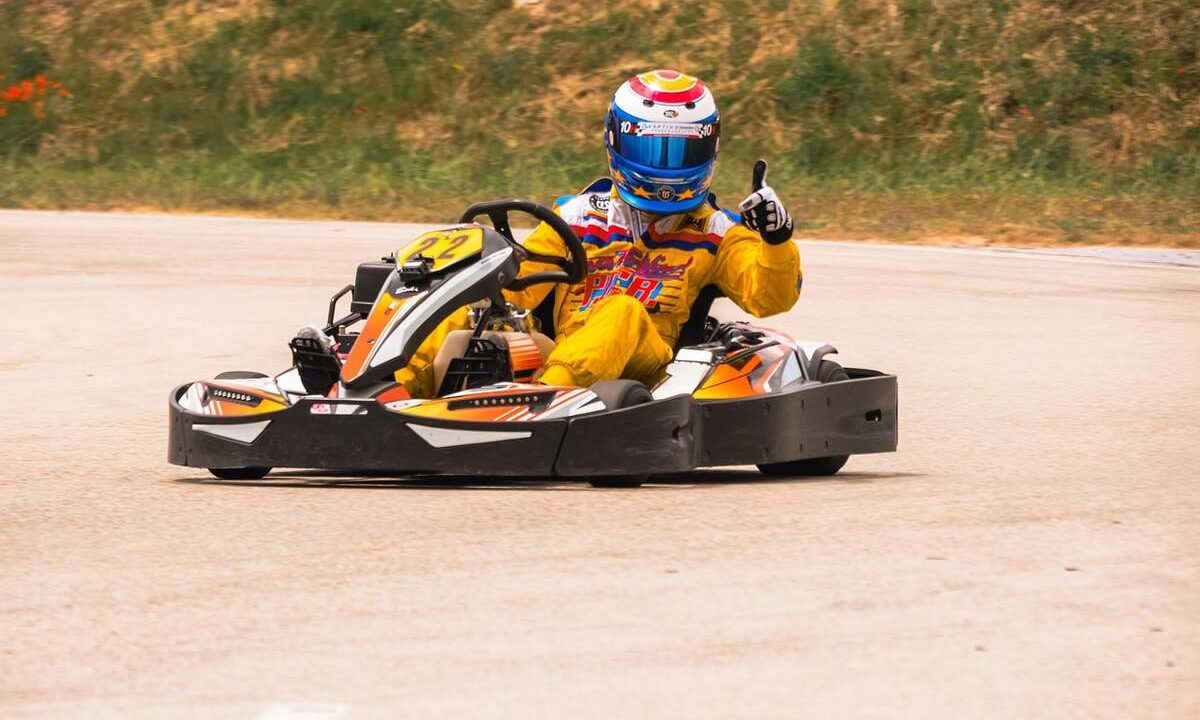 Un pilote de karting donne un signe de victoire sur la piste