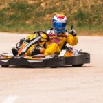 Un pilote de karting donne un signe de victoire sur la piste