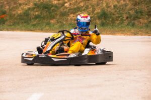 Un pilote de karting donne un signe de victoire sur la piste