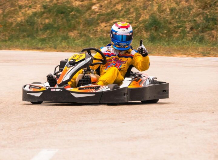 Un pilote de karting donne un signe de victoire sur la piste